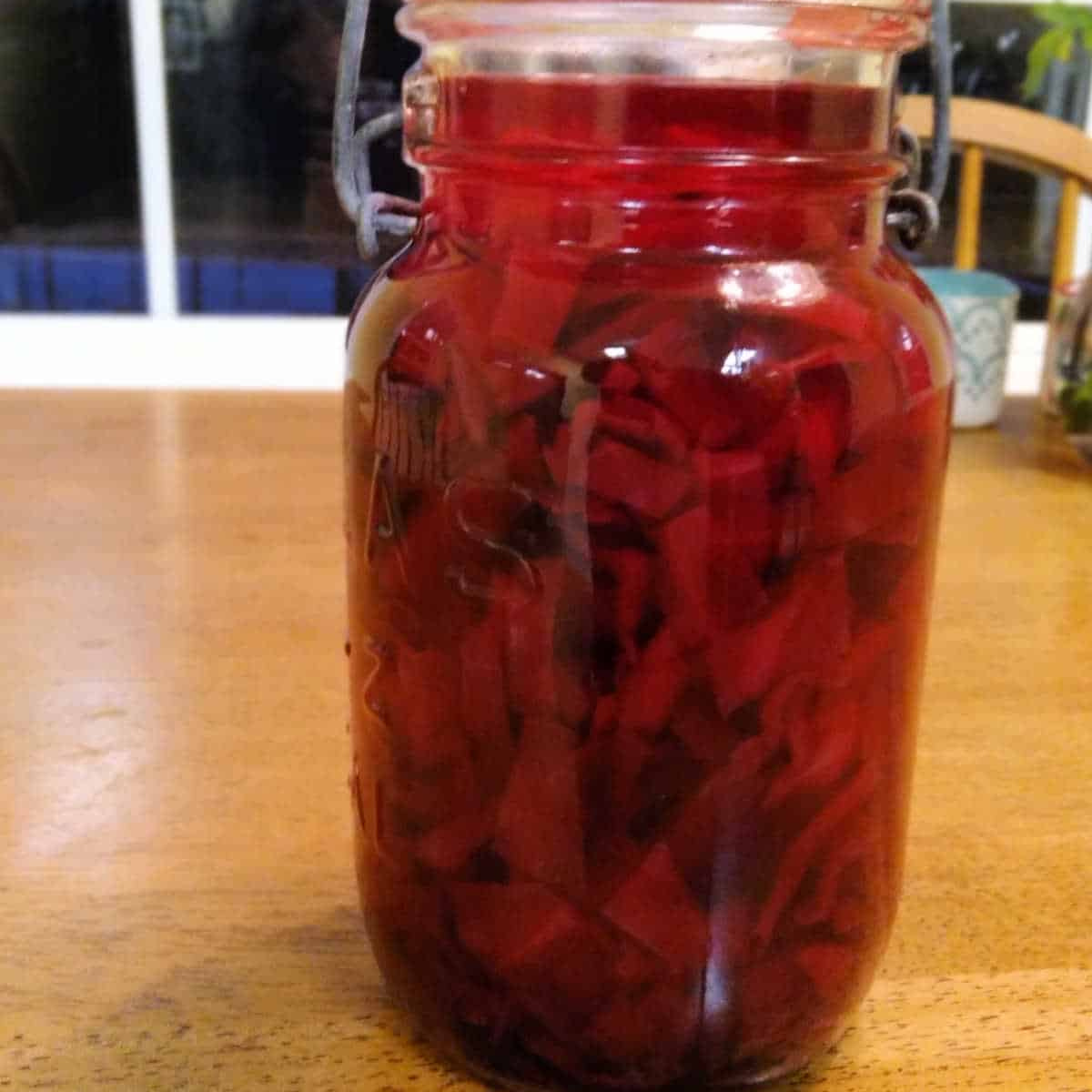 an old fashioned glass canning jar filled with beet and cabbage soup