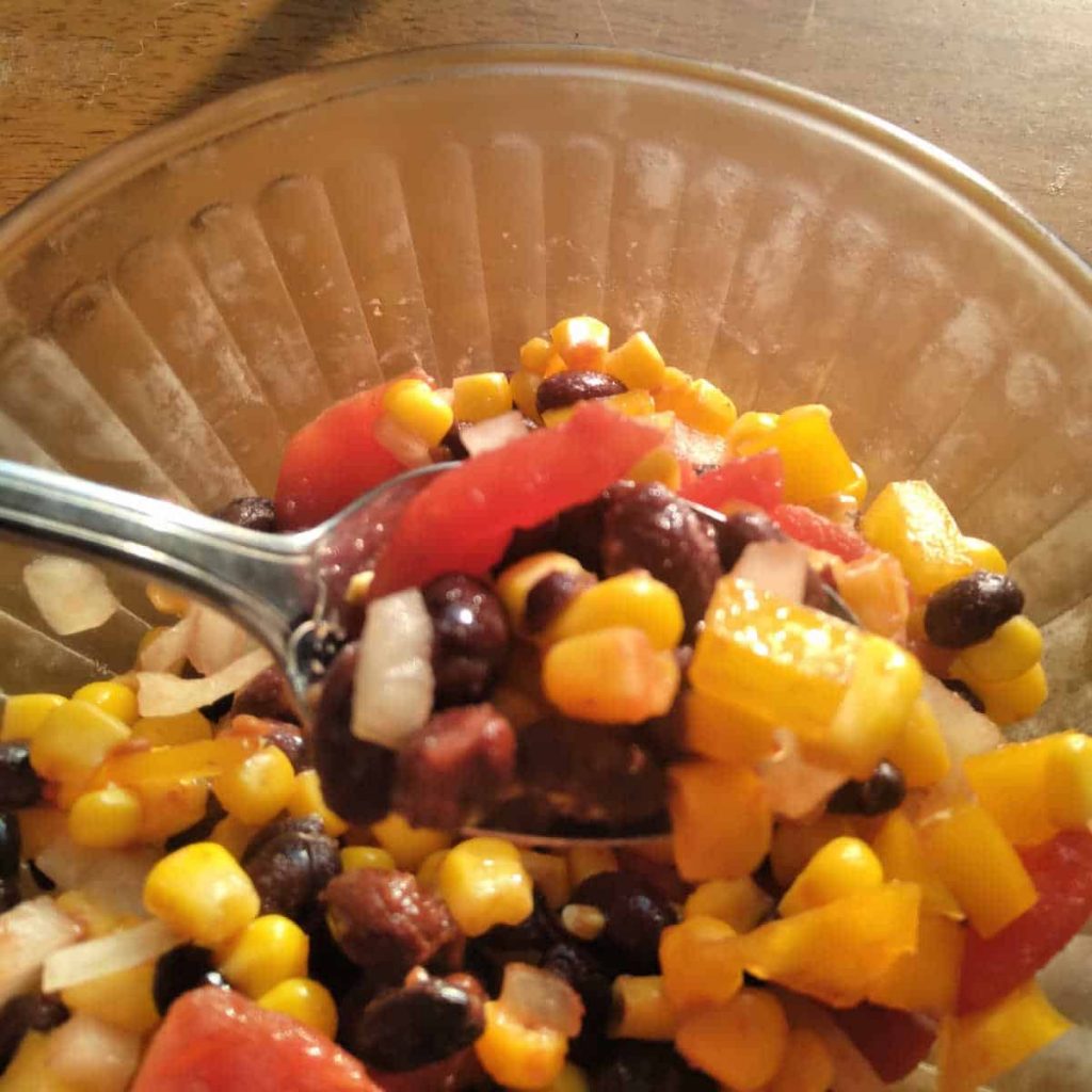 blak bean, corn, and tomatoes in a black bean salad in a bowl