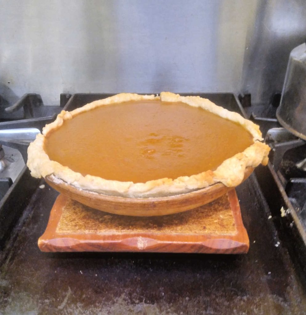 a homemade pumpkin pie cooling on the stove