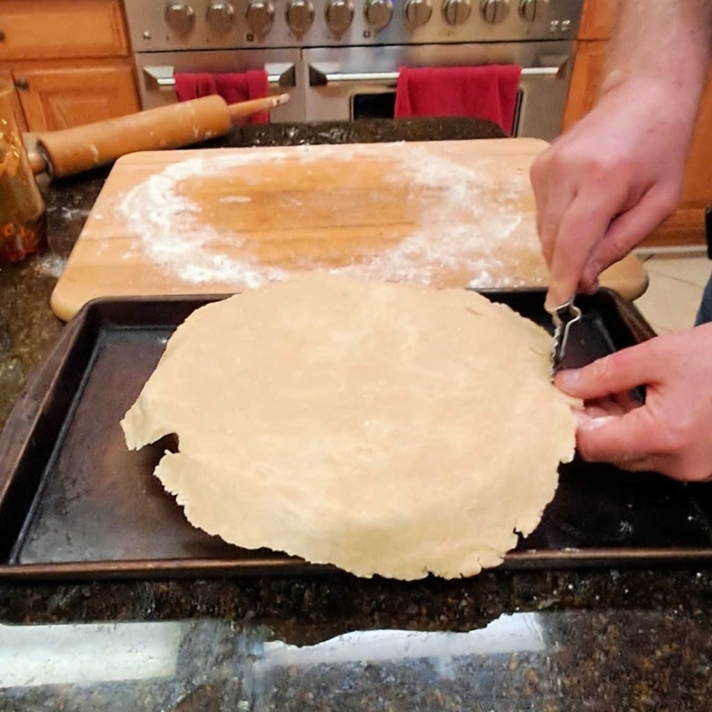 a man putting the top crust on a pie