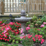 garden fountain with pink flowers around it